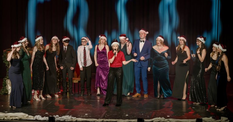 Ensemble der Musicalschule Ahrensburg in Weihnachtskostümen auf der Bühne während der Adventsshow "Als der Nikolaus kam"