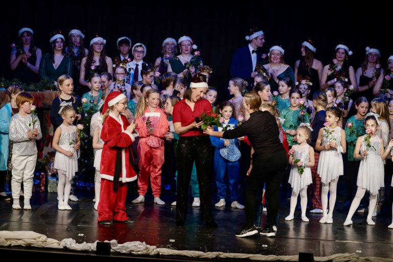 Adventsshow der Musicalschule Ahrensburg mit Kindern in Weihnachtskostümen und Elisabeth Hübert auf der Bühne.