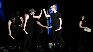 Theateraufführung "All Together Now" mit Schülern der Musicalschule Ahrensburg auf der Bühne in schwarzer Kleidung.