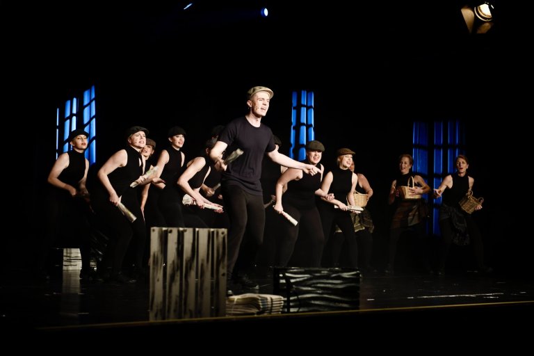 Tanzensemble der Musicalschule Ahrensburg performt auf Bühne mit Fedoras, schwarzer Kleidung und synchronisierten Choreographien.