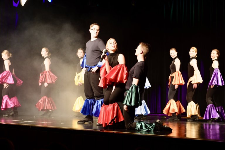 Schüler der Musicalschule Ahrensburg präsentieren bunte Kostüme auf einer beleuchteten Bühne während der Produktion "All Together Now".
