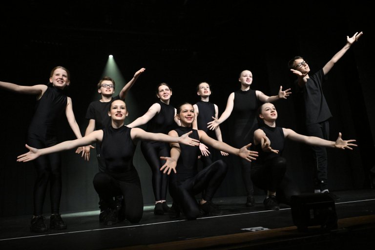 Gruppe junger Performer in schwarzer Kleidung auf Bühne, MSA10 Jubiläumsshow der Musicalschule Ahrensburg.