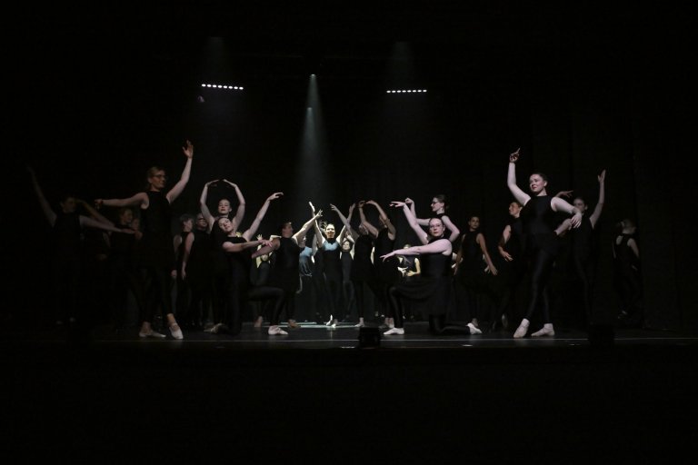 Tanzgruppe der Musicalschule Ahrensburg performt auf beleuchteter Bühne in schwarzen Kostümen zur Jubiläumsshow MSA10.