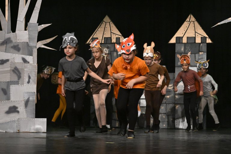 Kinder in Tierkostümen auf Bühne mit Schloss-Kulisse während Musicalaufführung der Musicalschule Ahrensburg.