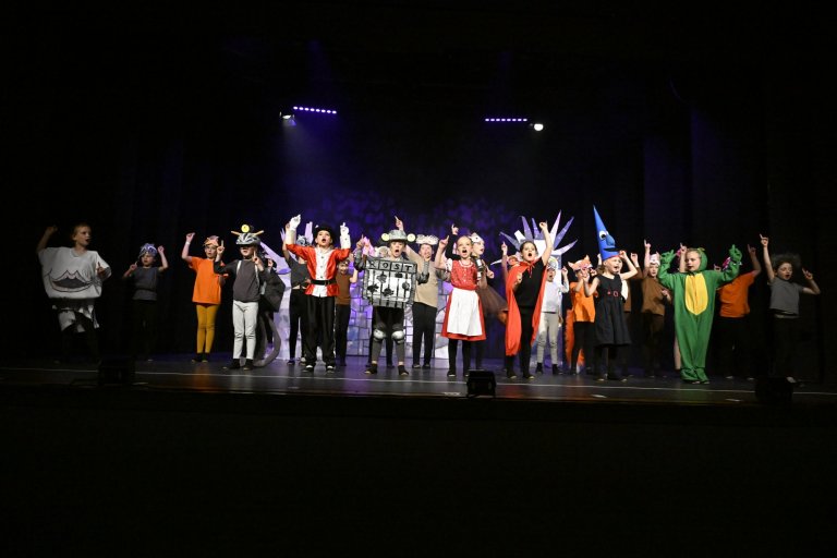Große Gruppe von Kindern in bunten Kostümen auf der Bühne der Jubiläumsshow MSA10 der Musicalschule Ahrensburg.