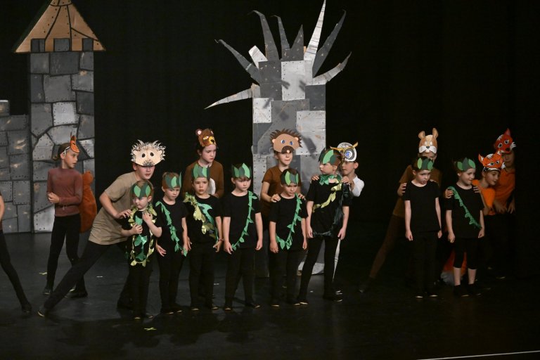 Kinder in Fantasie-Kostümen auf Theaterbühne mit Schloss und Baum-Kulisse während MSA10-Jubiläumsshow.