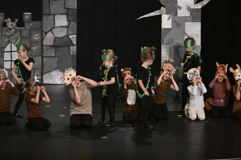 Kinder in Dinosaurier- und Tierkostümen performen auf Bühne mit Schlosskulisse zur Jubiläumsshow MSA10.