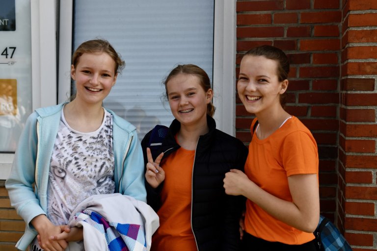 Drei lachende Schülerinnen der Musicalschule Ahrensburg beim Sommerfest 2022 vor Backsteinwand.