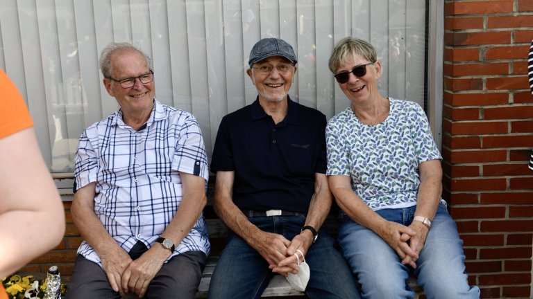 Drei lachende Erwachsene sitzen nebeneinander beim Musicalschule Ahrensburg Sommerfest 2022.