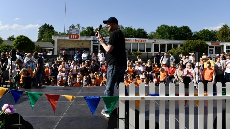 Moderator auf Bühne spricht zu Publikum beim MSA Sommerfest 2022 mit bunten Wimpeln und Kindern.