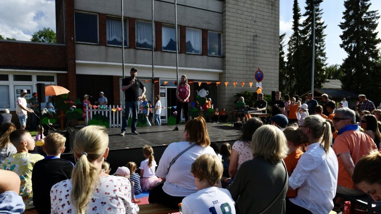 Musicalschule Ahrensburg Sommerfest 2022: Publikum verfolgt Bühnenauftritt mit orange Dekoration im Schulhof.