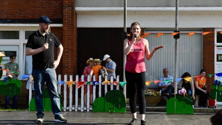 Zwei Performer auf Bühne beim MSA Sommerfest 2022: Mann joggt, Frau tanzt vor Publikum und bunten Dekorationen.