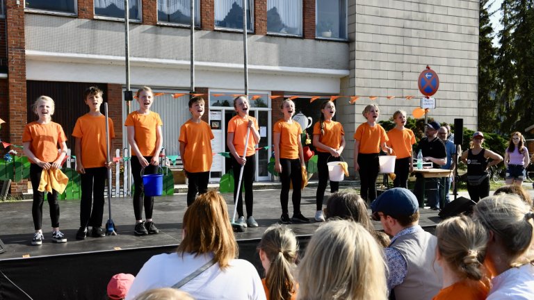 Kinderchortgruppe in orangefarbenen Shirts performt beim MSA Sommerfest 2022 vor Publikum auf Bühne.