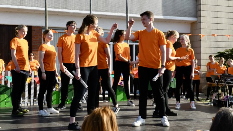 Musicalschüler in orangenen T-Shirts führen Tanzperformance beim Sommerfest 2022 der Musicalschule Ahrensburg auf.