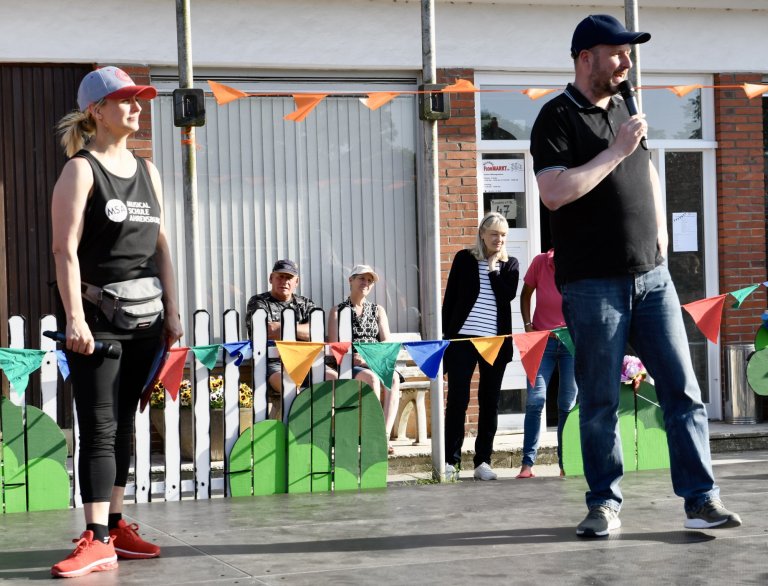 Musicalschule Ahrensburg Sommerfest 2022: Moderator und Tänzerin präsentieren auf festlich dekorierter Bühne vor Publikum.