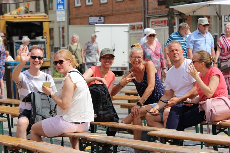 Besucher sitzen lachend an Biertischen beim Lindenfest Ludwigslust, genießen Getränke und sommerliche Atmosphäre.