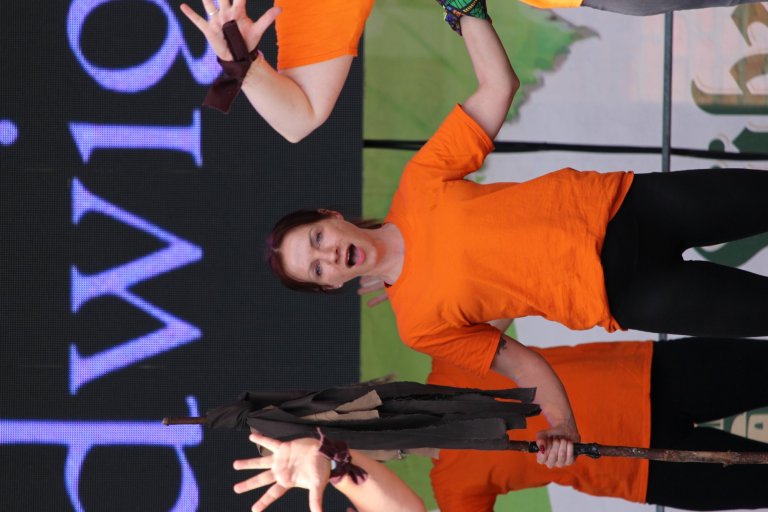 Schüler der Musicalschule Ahrensburg performt in orangem Shirt beim Lindenfest Ludwigslust vor LED-Bühne.