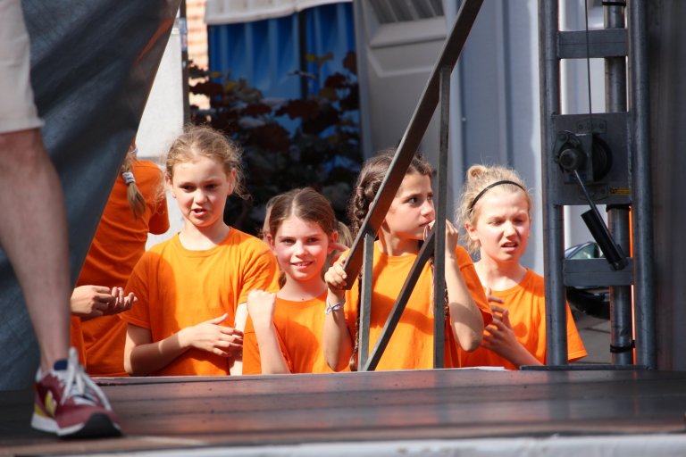 Vier Mädchen in orangefarbenen T-Shirts treten beim Lindenfest Ludwigslust auf der Musicalschule Ahrensburg auf.