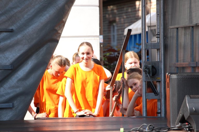 Kinder in orangefarbenen T-Shirts auf Bühne beim Lindenfest Ludwigslust, Musicalschule Ahrensburg Auftritt.