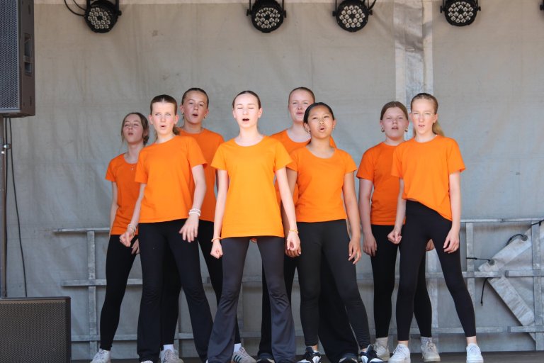 Kinder-Theatergruppe der Musicalschule Ahrensburg in orangenen Shirts beim Auftritt beim Lindenfest Ludwigslust.