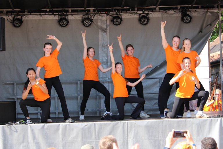 Musicalschule Ahrensburg Tanzgruppe in orange Shirts beim Lindenfest Ludwigslust auf der Bühne.