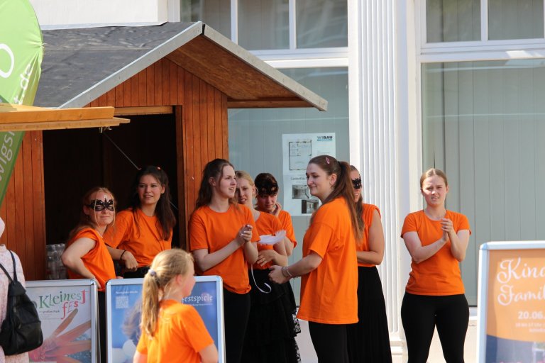Gruppe von Schülern in orangenen T-Shirts bei Auftritt beim Lindenfest Ludwigslust, Musicalschule Ahrensburg Performance.