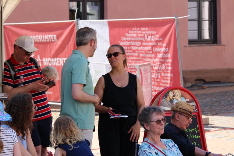 Besucher beim Lindenfest Ludwigslust: Mitarbeiter informieren Publikum an rotem Informationsstand der Musicalschule Ahrensburg.