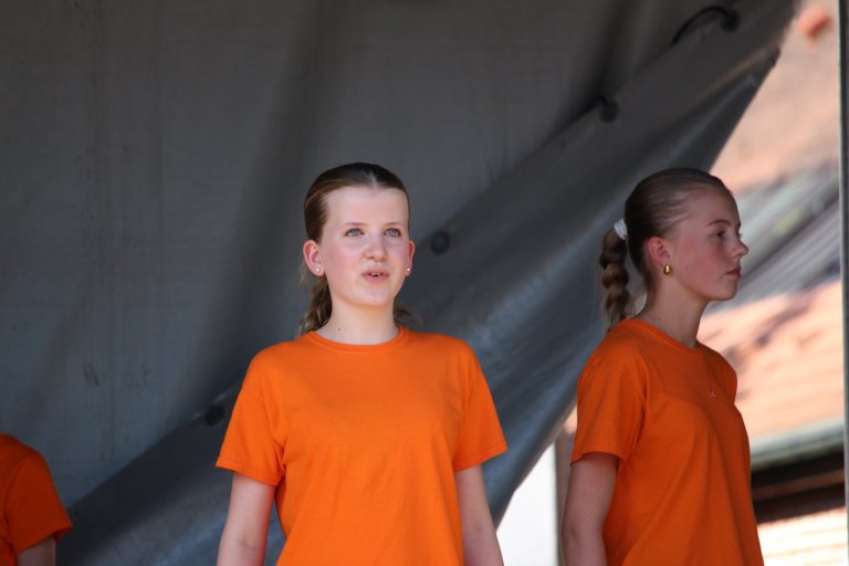 Zwei junge Mädchen in orangen T-Shirts beim Lindenfest Ludwigslust der Musicalschule Ahrensburg.