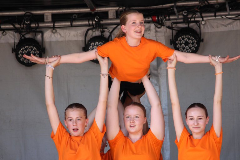 Vier Mädchen in orangefarbenen Shirts führen eine Pyramide-Formation auf der Bühne beim Lindenfest Ludwigslust auf.