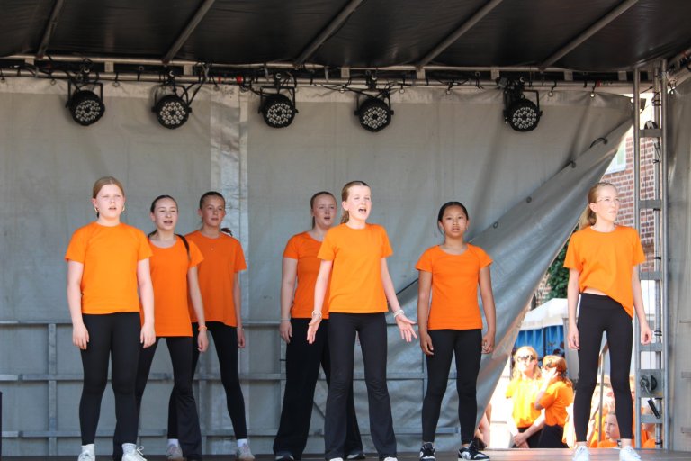 Gruppe junger Sänger in orangenen Shirts präsentiert sich auf Bühne beim Lindenfest Ludwigslust.