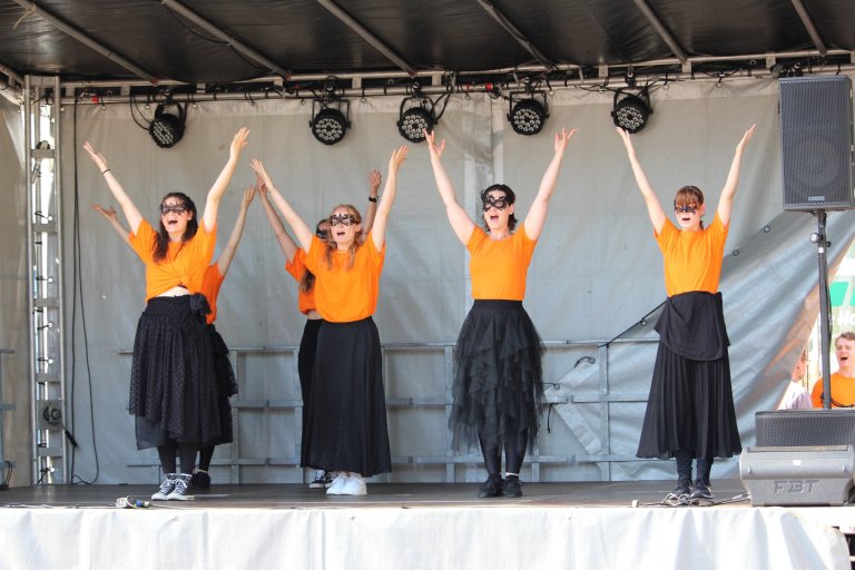 Vier Mädchen der Musicalschule Ahrensburg performen auf der Bühne des Lindenfests Ludwigslust in gelben Shirts und schwarzen Röcken.